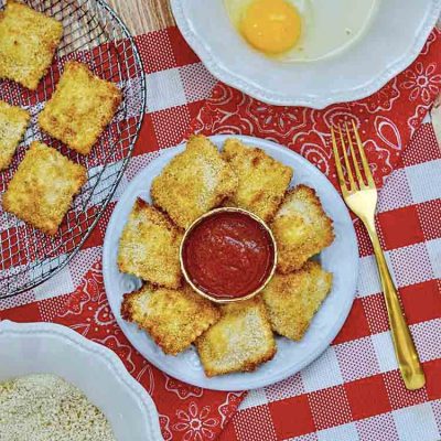 A table set with air fryer ravioli recipe ingredients and a platter of finished ravioli.