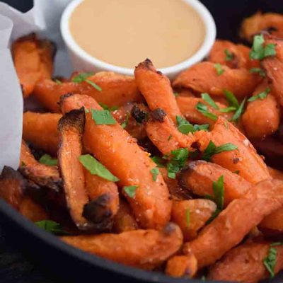 A black skillet filled with Air Fryer Sweet Potato Fries and a side of fry dip.