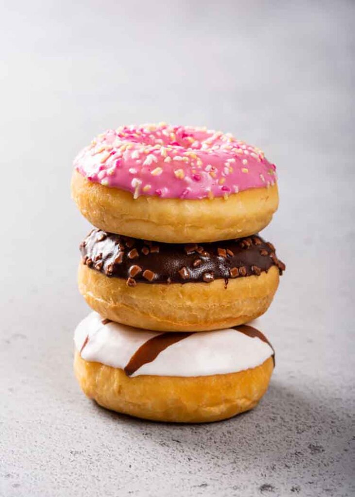 Can You Bake In An Air Fryer? Stack of colorful donuts on gray concrete background.