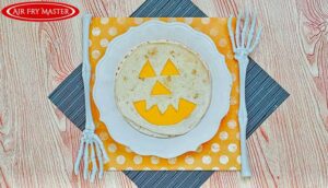 An overhead view looking down onto a white plate with an Air Fryer Jack-O-Lantern Quesadilla on it.