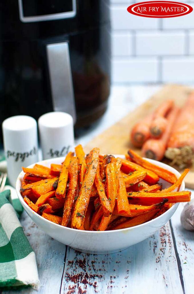 Front view of a white bowl filled with Air Fryer Carrot Fries.